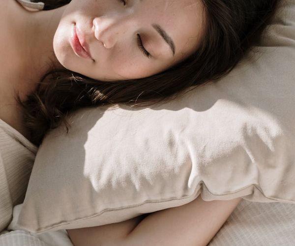 Person stretching gently indoors, illuminated by soft morning light.